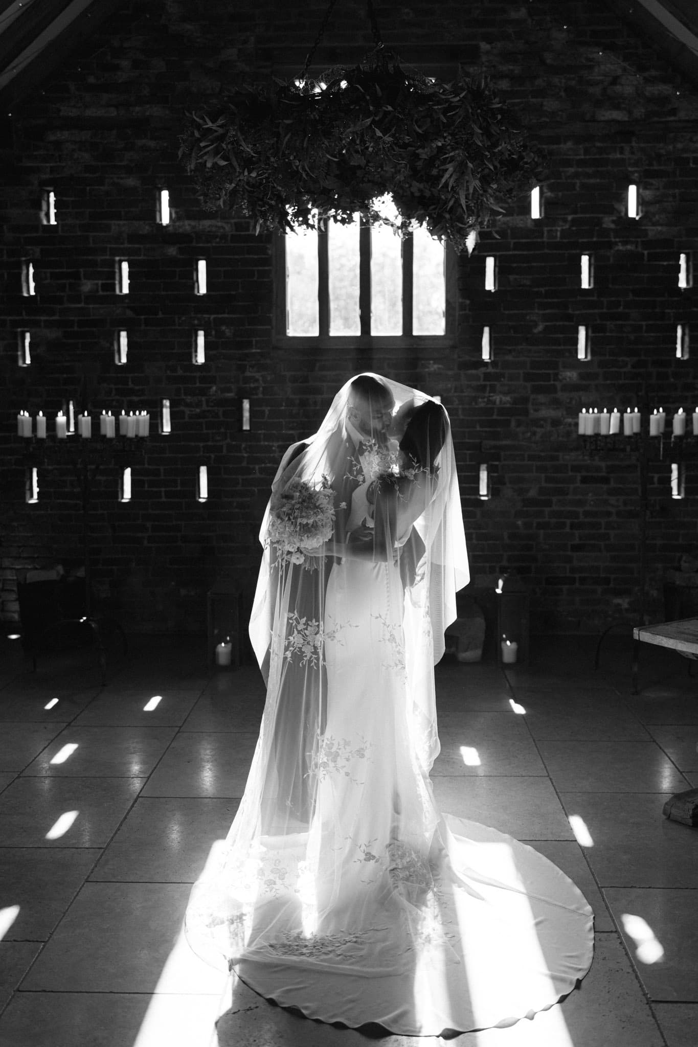 A couple beneath a veil in the ceremony barn at Grangefields